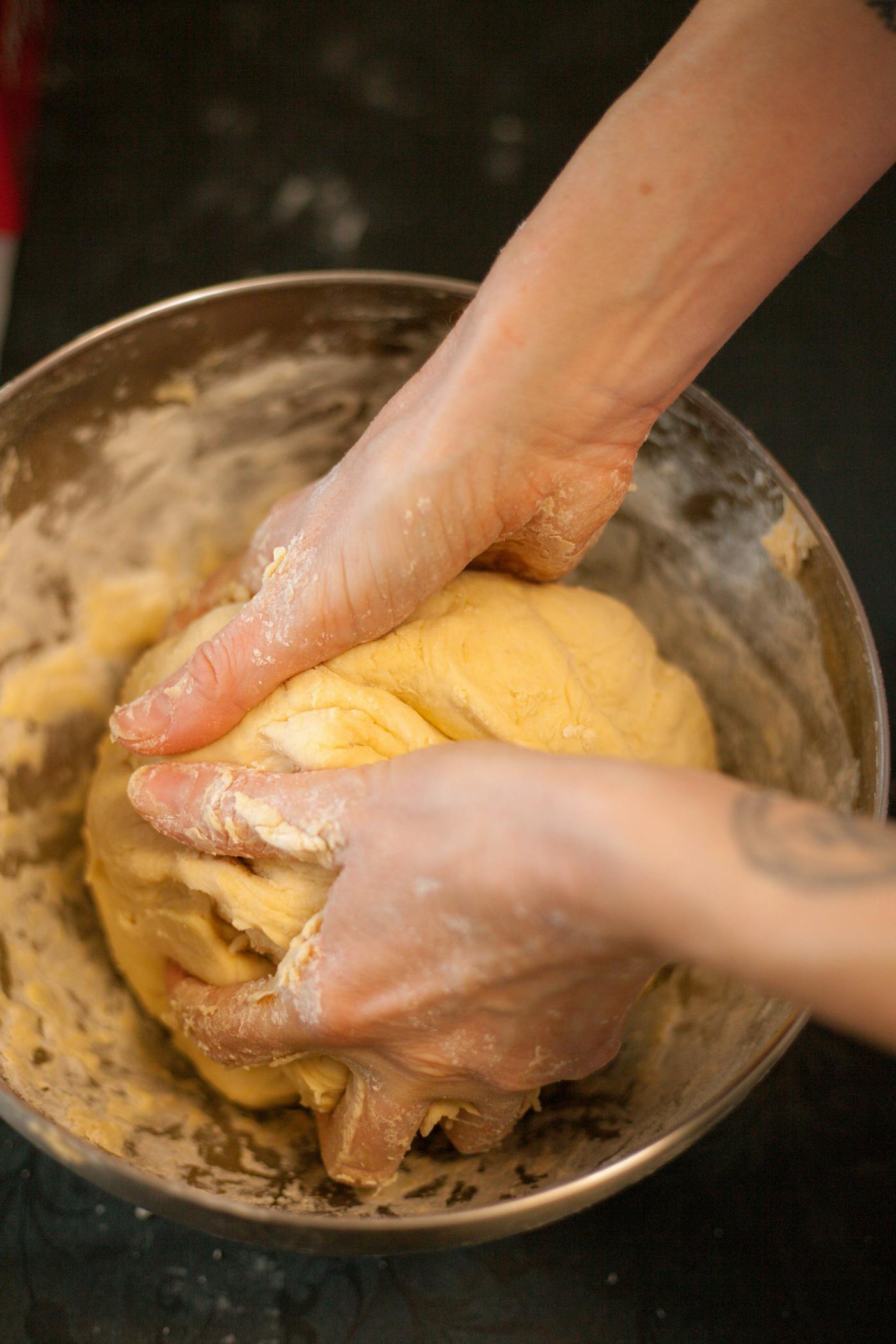 Flour-dusted hands shaping a round of dough on a stone bench.