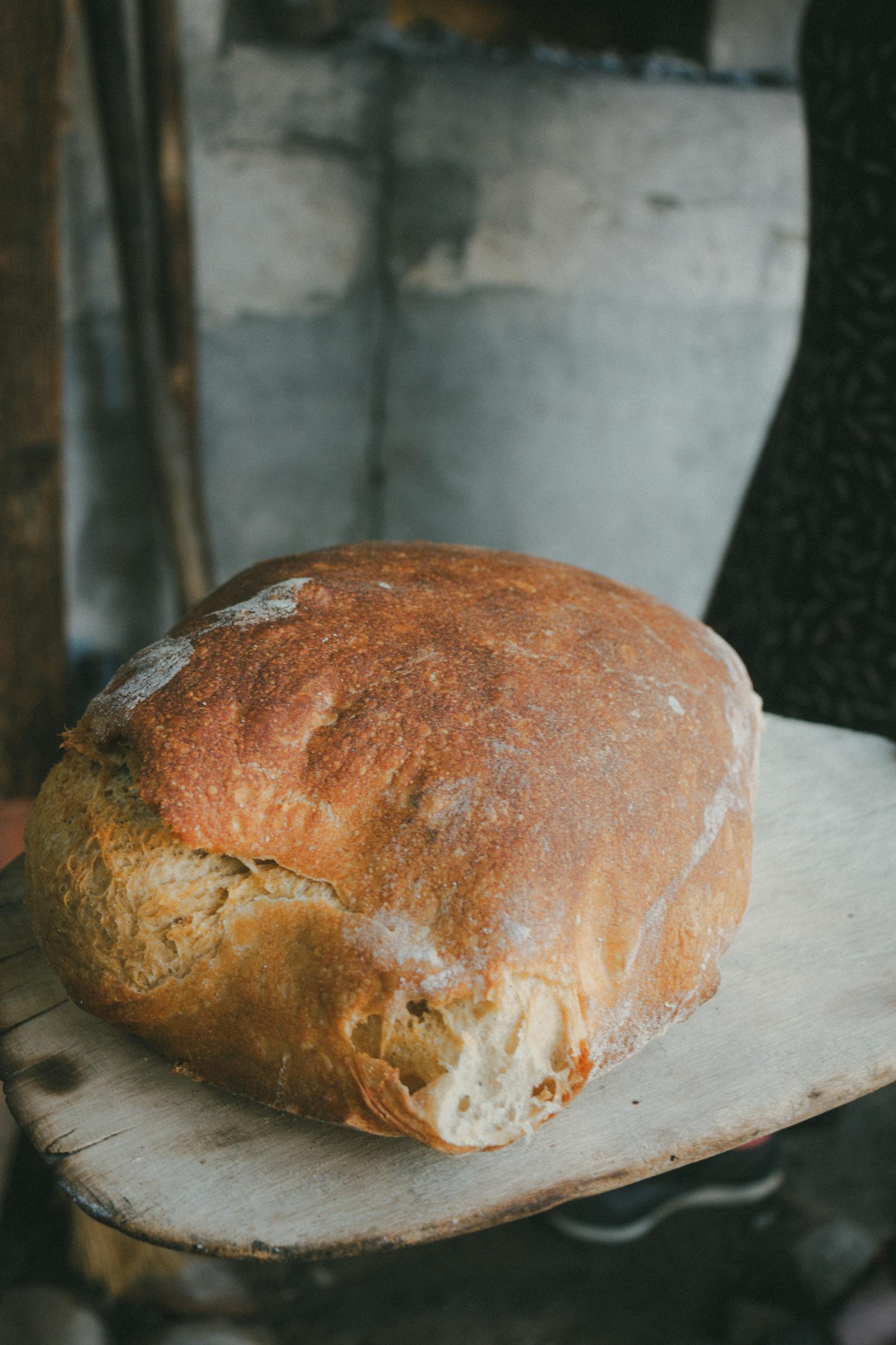 A dark-crusted country loaf cooling on a linen cloth.